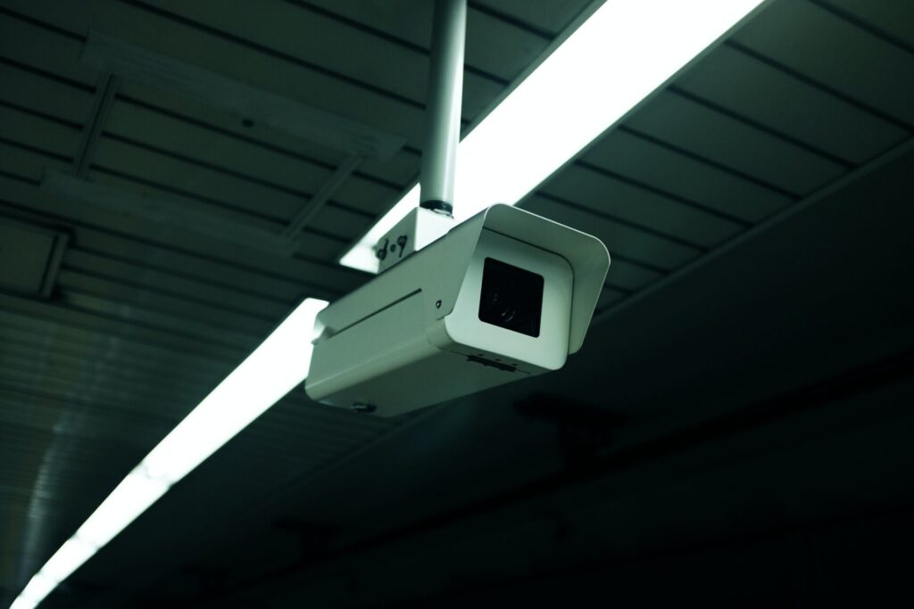 A white and black security camera mounted on an indoor ceiling.